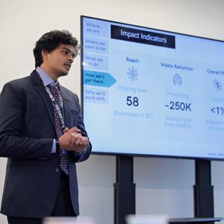 Tejas giving a presentation next to a powerpoint slide.