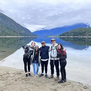 A group of five students with a lake in the background