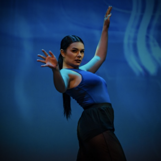 Taylor Fleming on stage during a dance performance against a blue backdrop