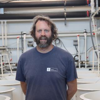 Tim Green standing in the tank room and looking at the camera at VIU Deep Bay Station