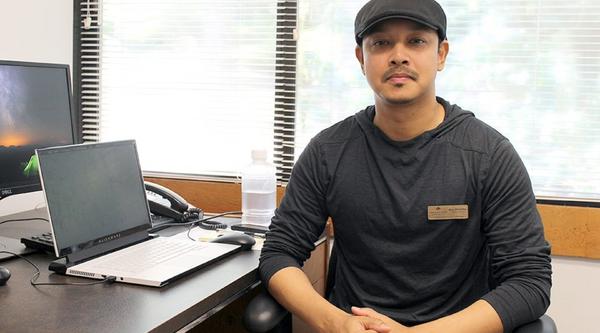 AJ sits at his desk