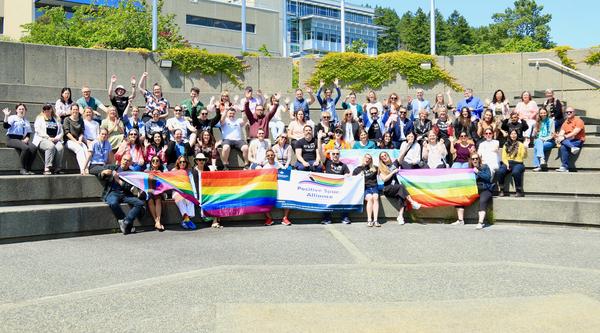 a group of people wearing VIU Pride shirts and holding up pride flags