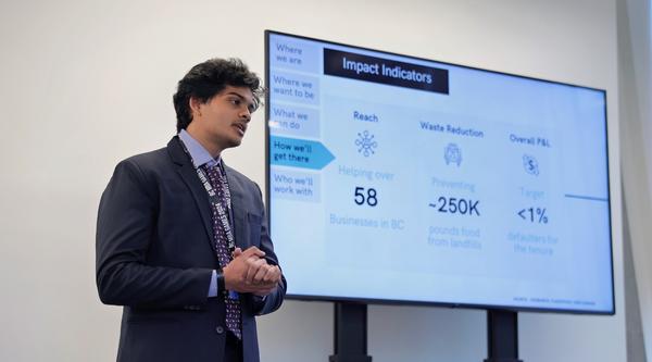 Tejas giving a presentation next to a powerpoint slide.