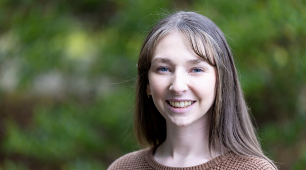 Kendra Neary outside smiling at the camera against a green backdrop