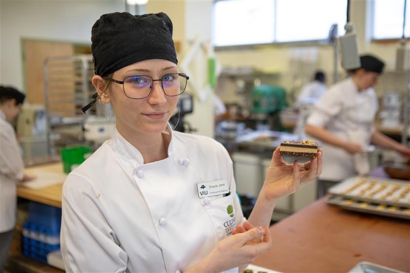 a baking student holds up a Nanaimo bar