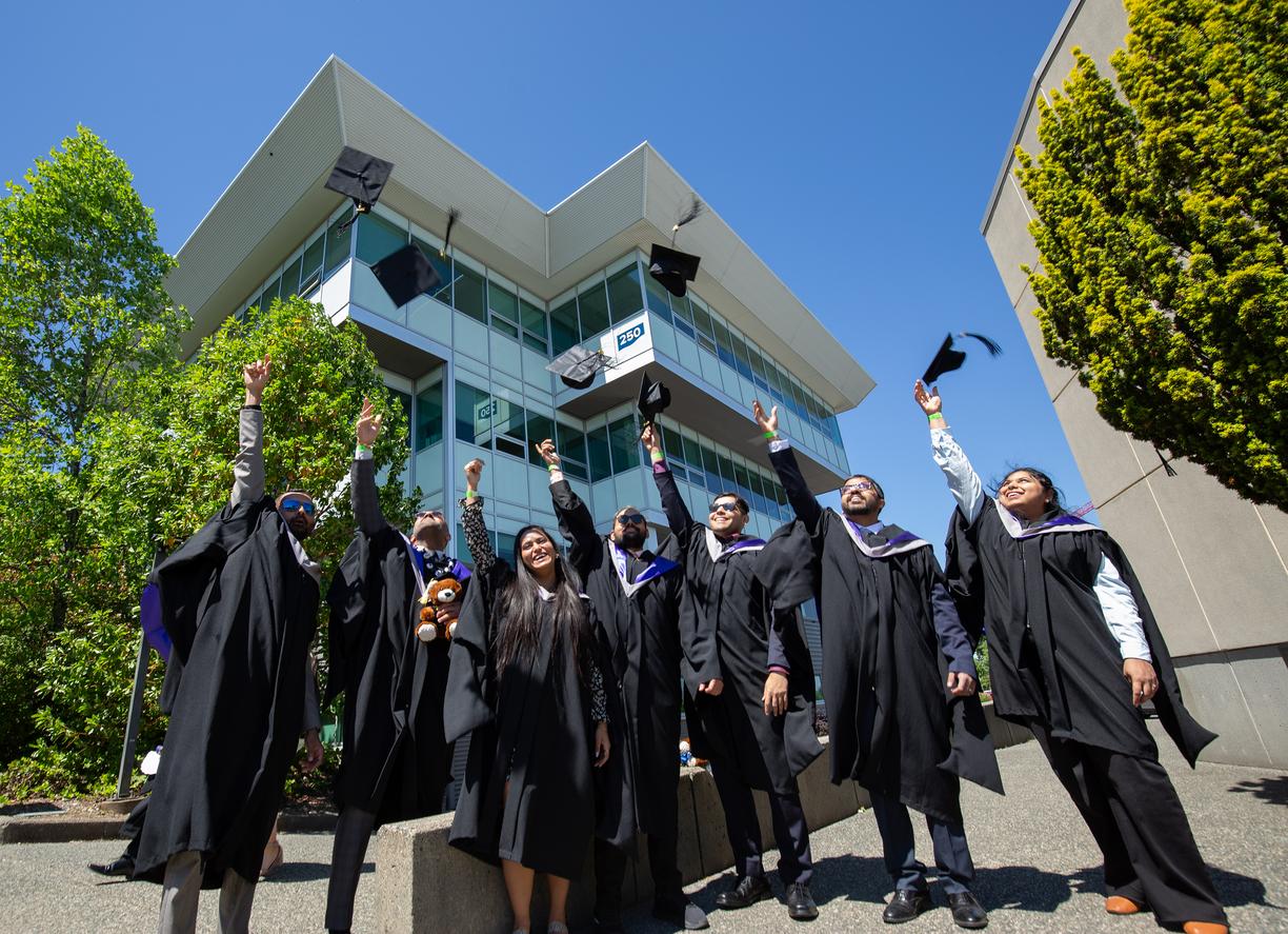 students in regalia throw their grad caps in the air