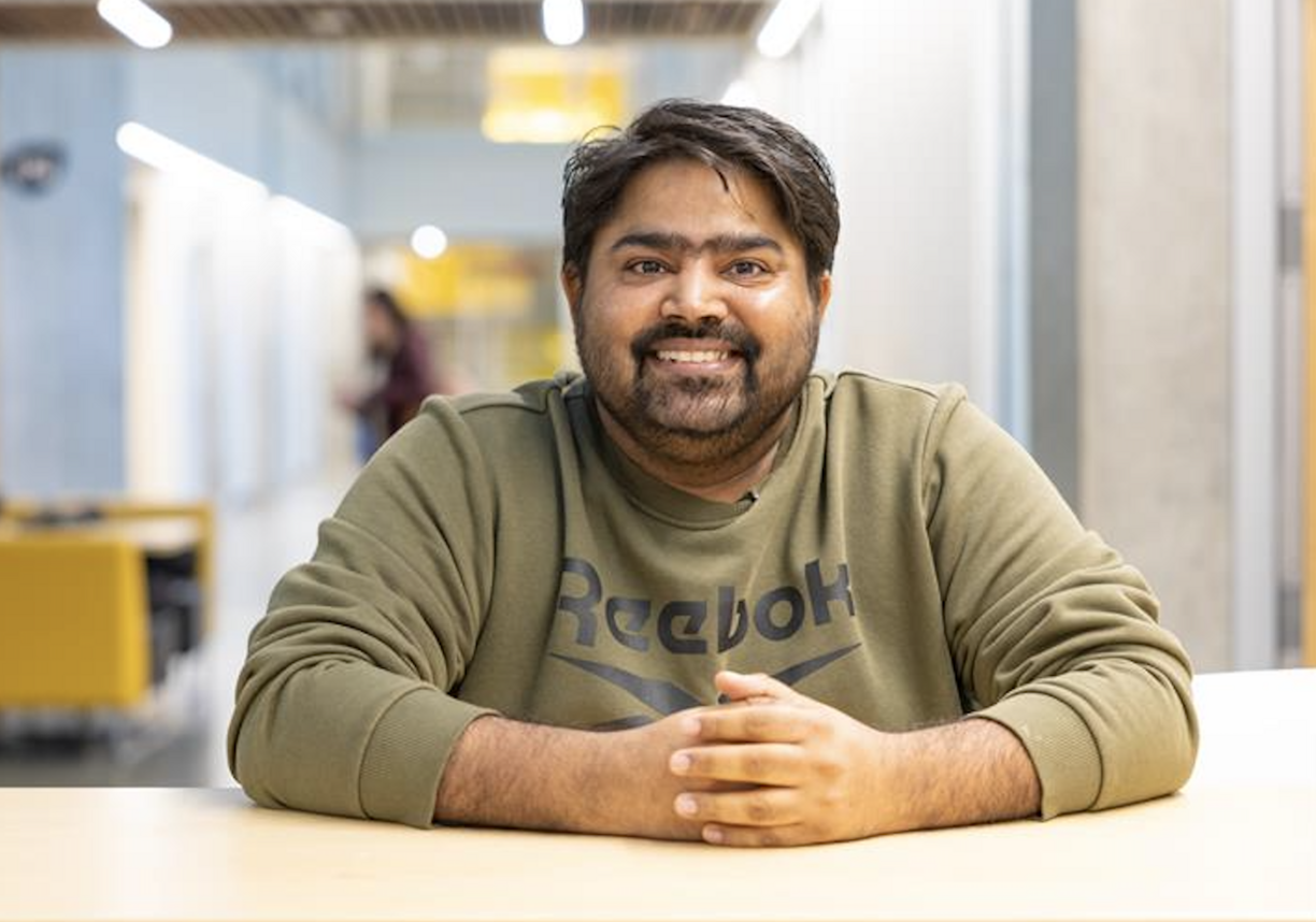 Lavdeep sitting at a table and smiling at the camera.