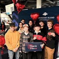 Group of happy young people holding up a sign that reads "thank you."